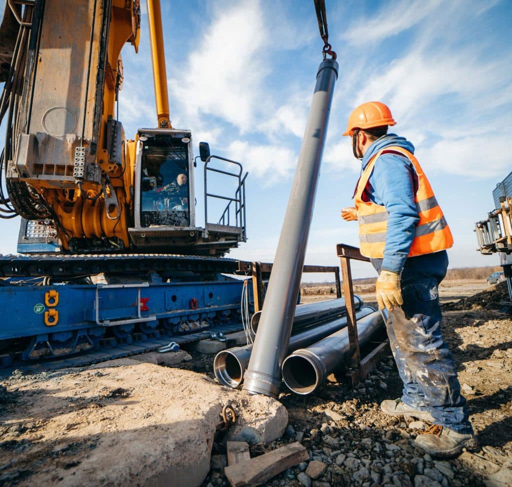 Construction worker guiding pipeline during installation